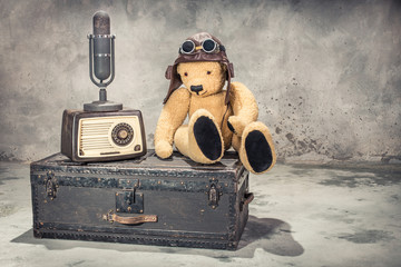 Retro radio, studio microphone, Teddy Bear toy with leather aviator's hat and goggles sitting on...
