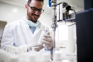 Technologist filling bottles with liquid soap while standing in cosmetic lab.