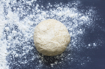 fresh raw baking dough sprinkled with flour on a dark background