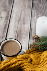 Obraz na płótnie Canvas Cup of coffee with milk, candle, bumps, spruce branches and warm orange scarf on wooden table.Winter concept. Flat lay, top view. 
