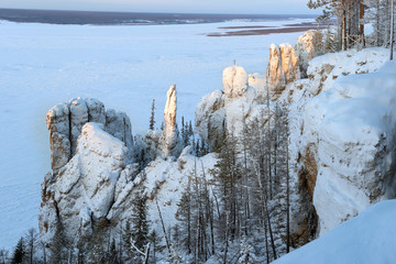 winter mountains landscape with trees and blue sky. Stone Pillars in the Natural Park Lenskie...