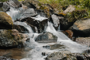 Flowing Water cascade of Mountain River with Bed Stones streaming down in the forest