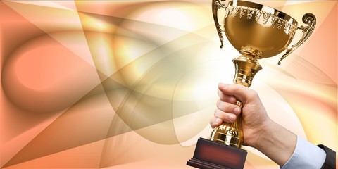 Hand holding golden trophy on blurred background