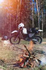 campfire summer day in forest. off road motorcycle, enduro bike, biker resting outdoors, vertical photo
