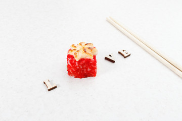 Creative photo sushi. Love for sushi. One red roll, chopsticks and the inscription love on a light background.