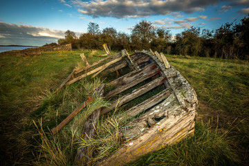 Fototapeta na wymiar Obsolete small boats and barges were beached on the banks of the tidal River Severn in Gloucestershire, UK to protect the river banks from erosion