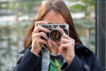 Portrait of a pretty young tourist taking photographs with vintage retro camera