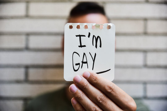 young man showing a note with the text I am gay