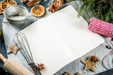 Empty cookbook for Christmas recipes, on dark blue concrete background with ingredients for traditional xmas baking, top view copy space