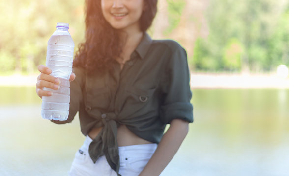 Hand of Asian woman holding a plastic bottle clean water drinking water after workout exercising or walking outdoor. clean water are good for health and recovery concept