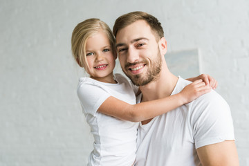 happy father and cute little daughter hugging and smiling at camera