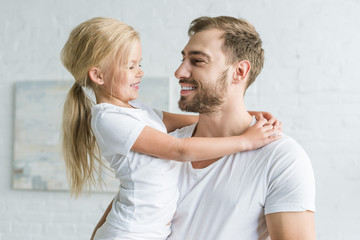 happy father and cute little daughter hugging and smiling each other at home