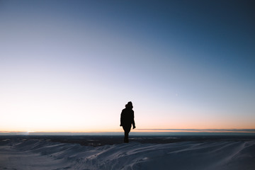 Fototapeta na wymiar man walking on snow at sunset / sunrise