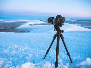 DLSR digital camera on tripod in nature with snow