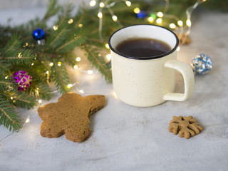 Christmas background with Gingerbread cookies, cup of tea. Cozy evening, Christmas decorations, colored balls and lights garlands. New Year card. Place for text, selective focus