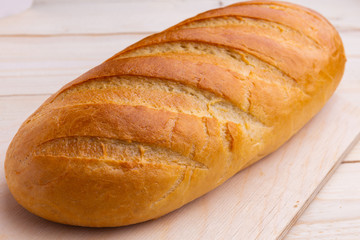 loaf of fresh baked bread on wooden background desk, closeup, traditional russian