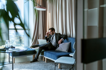 Businessman using laptop while sitting in chair in modern office.