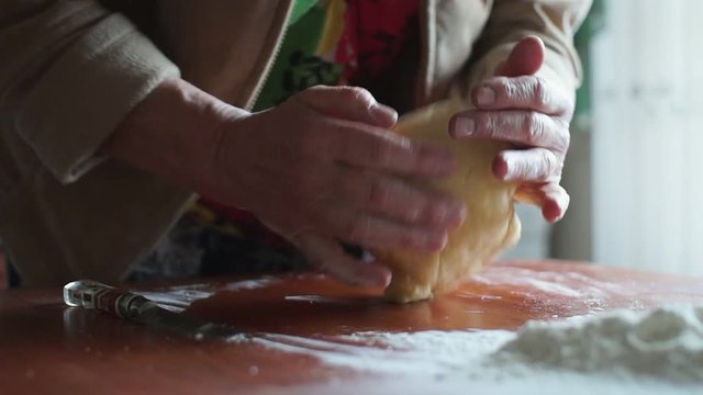 Woman kneading dough in flour on table