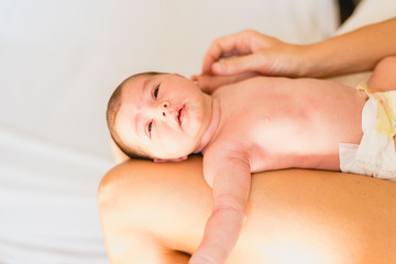 Newborn naked on the legs of his mother.