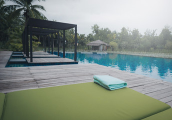 Green Towel on the sun bed near swimming pool. Vintage tone