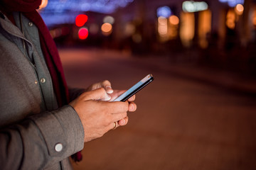 Male person using mobile phone outdoors at night.