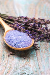 Cosmetic salt for bath in a spoon with flowers lavender p on a wooden background with copy space.