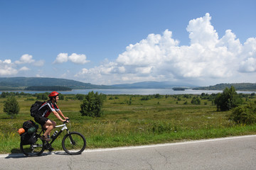 Cyclist with a saddle bag near a lake. Traveler on bicycle on sunny day