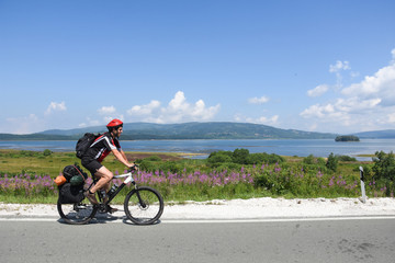 Fototapeta na wymiar Cyclist with a saddle bag near a lake. Traveler on bicycle on sunny day