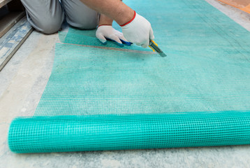 A worker is cutting  a fiberglass mesh.