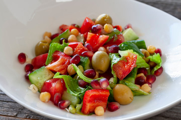 Fruit and vegetable salad: olives, pomegranate seeds, sweet peppers, corn, sprouted seeds and lettuce leaves.