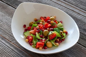 Fruit and vegetable salad: olives, pomegranate seeds, sweet peppers, corn, sprouted seeds and lettuce leaves.