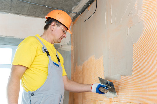 The construction worker putty a wall.