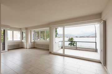 Fototapeta na wymiar Empty room with radiators and large window overlooking Lake Lugano
