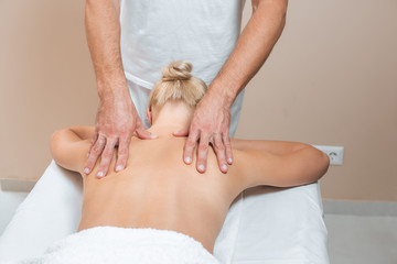 Male masseur doing back massage to woman in spa room