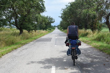 Cyclist with a saddle bag on the road. Traveler on bicycle on long way