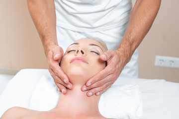 Fototapeta na wymiar Male therapist doing face massage to woman in beauty salon