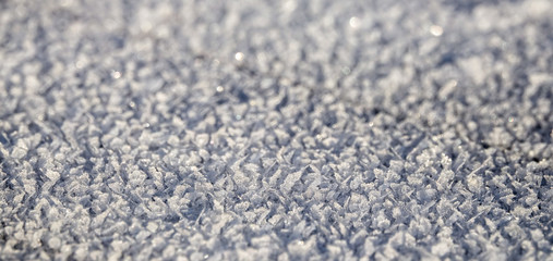 Frozen crystals on frost and snow in the sun outdoors. Empty background for copy space.