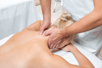 Obraz na płótnie Canvas male masseur doing neck massage to woman in spa