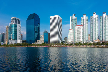 Fototapeta premium Business district Bangkok capital city skyline during day time blue sky with lake view from Benjakitti Park.