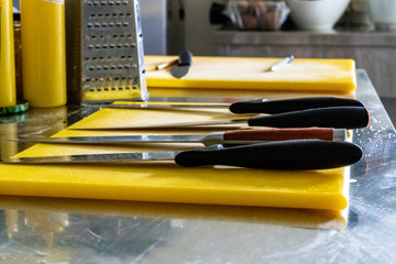 Sharp Knives with Black Handles Laying on Table with Yellow Board