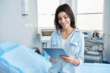 Waist up photo of pretty lady holding tablet in her hands and filling out questionnaires. Copy space on left side