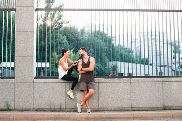 In love with sport. Young beautiful couple in sportswear bonding to each other while standing against industrial city view