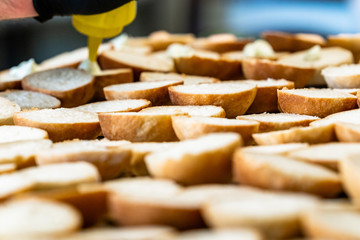 Male Chef Spreading the Sauce on the Sliced Bread Spread on a Table for Small Burgers