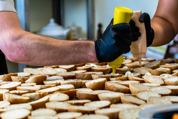 Male and Female Chef Spreading the Sauce on the Sliced Bread Spread on a Table for Small Burgers