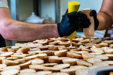 Male and Female Chef Spreading the Sauce on the Sliced Bread Spread on a Table for Small Burgers