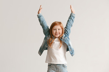 Full length portrait of cute little kid girl in stylish jeans clothes looking at camera and...