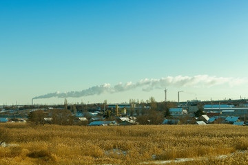Fototapeta na wymiar smoke from the chimney of the boiler house, stretching for kilometers in the blue sky