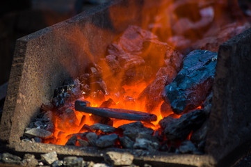 blacksmith furnace with burning coals, tools, and glowing hot horseshoe
