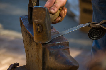 blacksmith performs the forging of hot glowing metal on the anvil