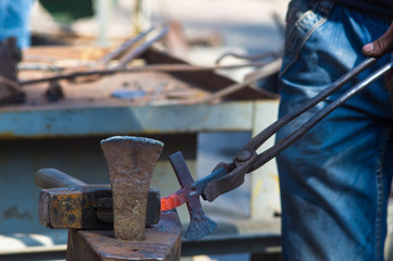 blacksmith performs the forging of hot glowing metal on the anvil